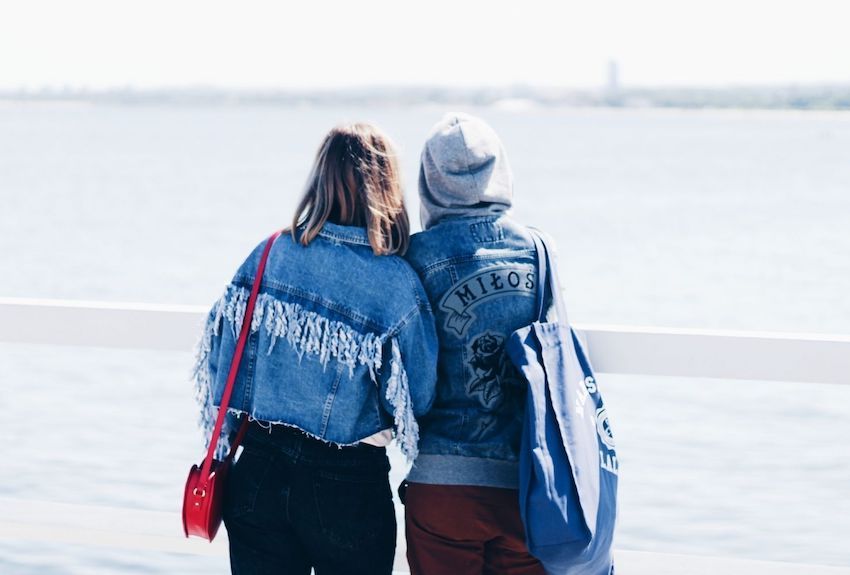 two-people-on-beach-looking-out-at-water-leaning-on-each-other-850.jpeg